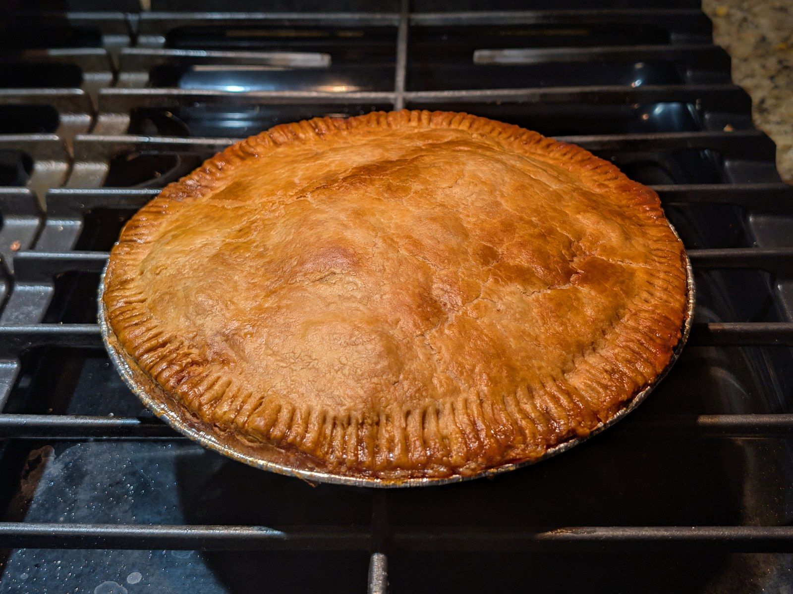 A golden double-crust apple pie on the stove